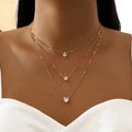Fine gold chain with three small pendants at varying drop lengths. By Sophi.