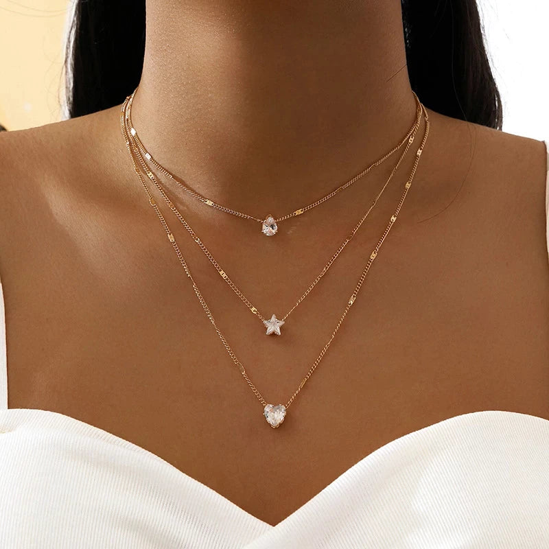 Fine gold chain with three small pendants at varying drop lengths. By Sophi.