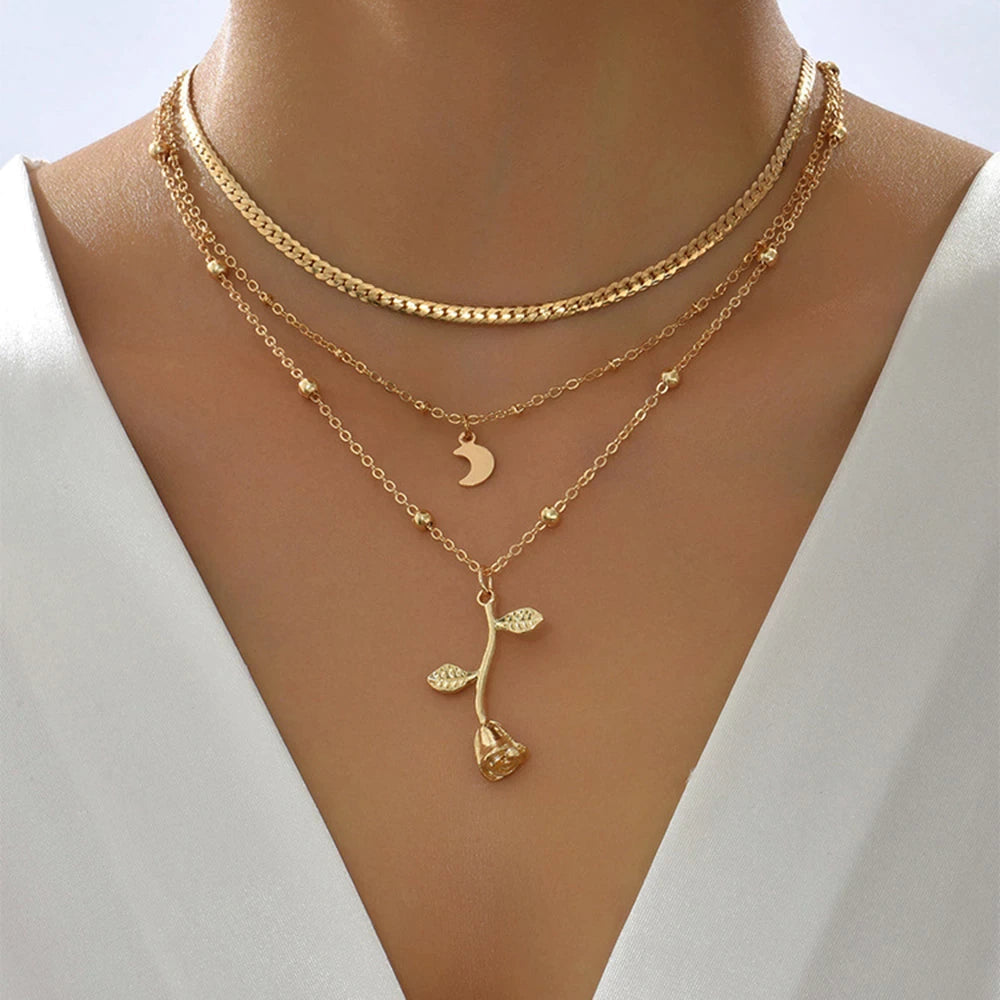 Gold chain necklace with a small rose outline and crescent moon pendant. By Sophi.