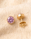 By Sophi Amethyst Birthstone Studs flat-lay on warm cream wool