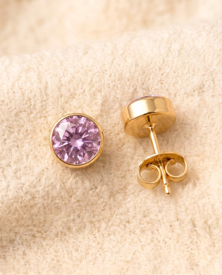 By Sophi Amethyst Birthstone Studs flat-lay on warm cream wool