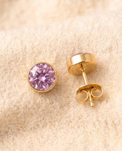 By Sophi Amethyst Birthstone Studs flat-lay on warm cream wool