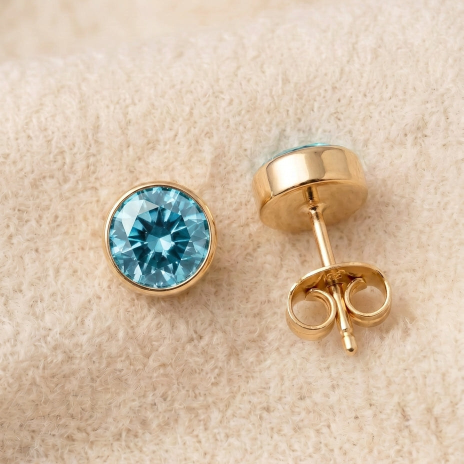 By Sophi Aquamarine Birthstone Studs flat-lay on warm cream wool