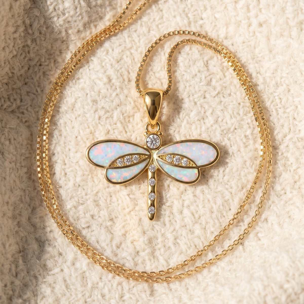 By Sophi Dragonfly Necklace in Gold with Opal flat-lay on warm cream