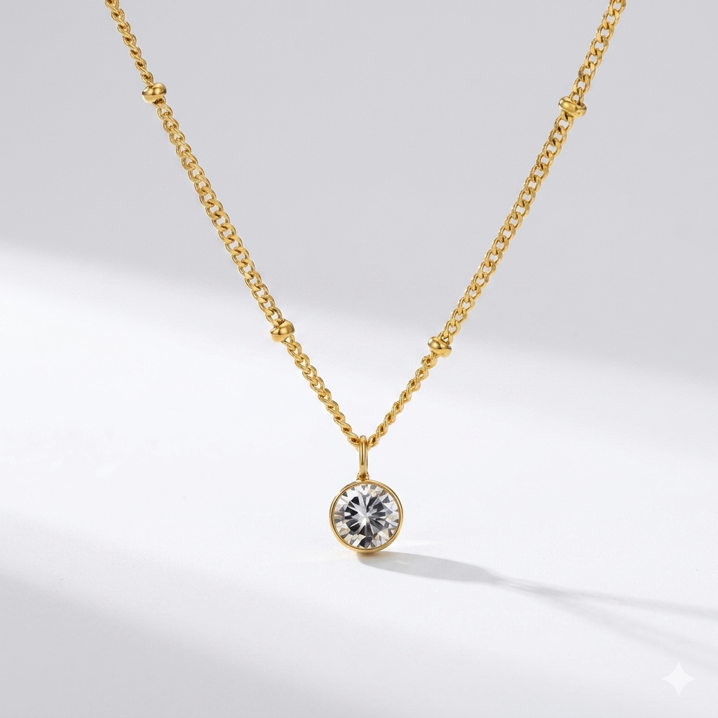 Diamond birthstone pendant necklace in gold-toned chain on cream background. By Sophi.