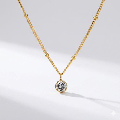 Diamond birthstone pendant necklace in gold-toned chain on cream background. By Sophi.