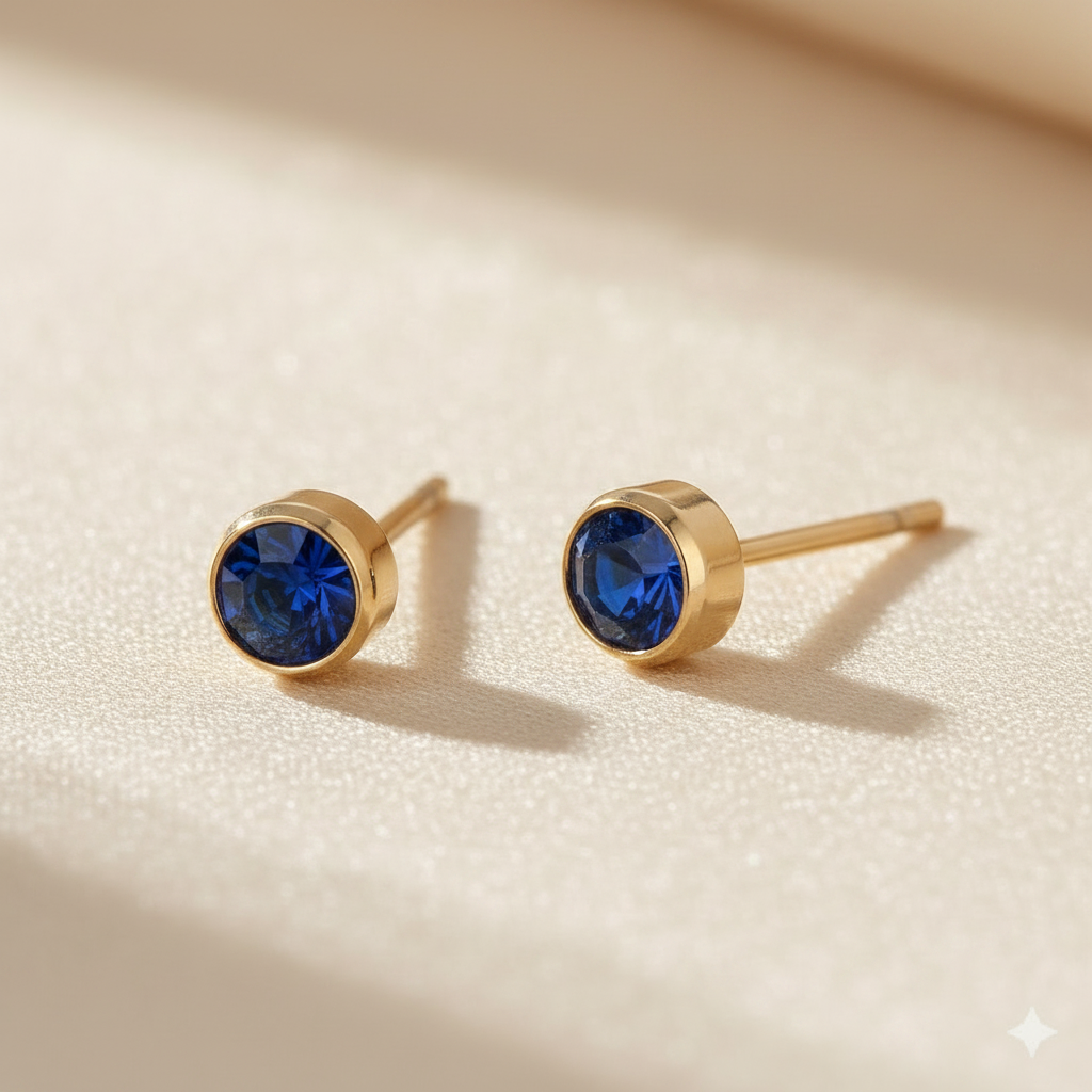 Sapphire birthstone stud earrings in gold-toned bezel. By Sophi.
