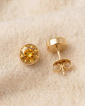 By Sophi Citrine Birthstone Studs flat-lay on warm cream wool