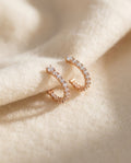 By Sophi Elegant Rounded Zirconia Earrings flat-lay on warm cream wool