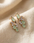 By Sophi Elegant Green Wings Crystal Earrings flat-lay on warm cream wool