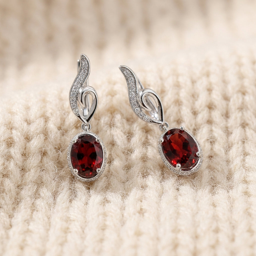 Natural red garnet drop earrings in sterling silver on warm cream wool