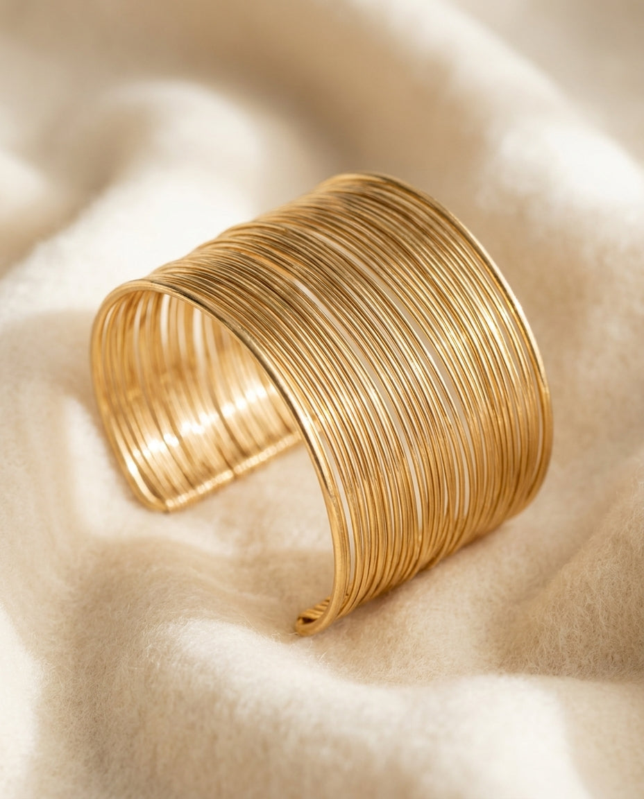 By Sophi Vintage Gold Wire Cuff Bracelet flat-lay on warm cream wool