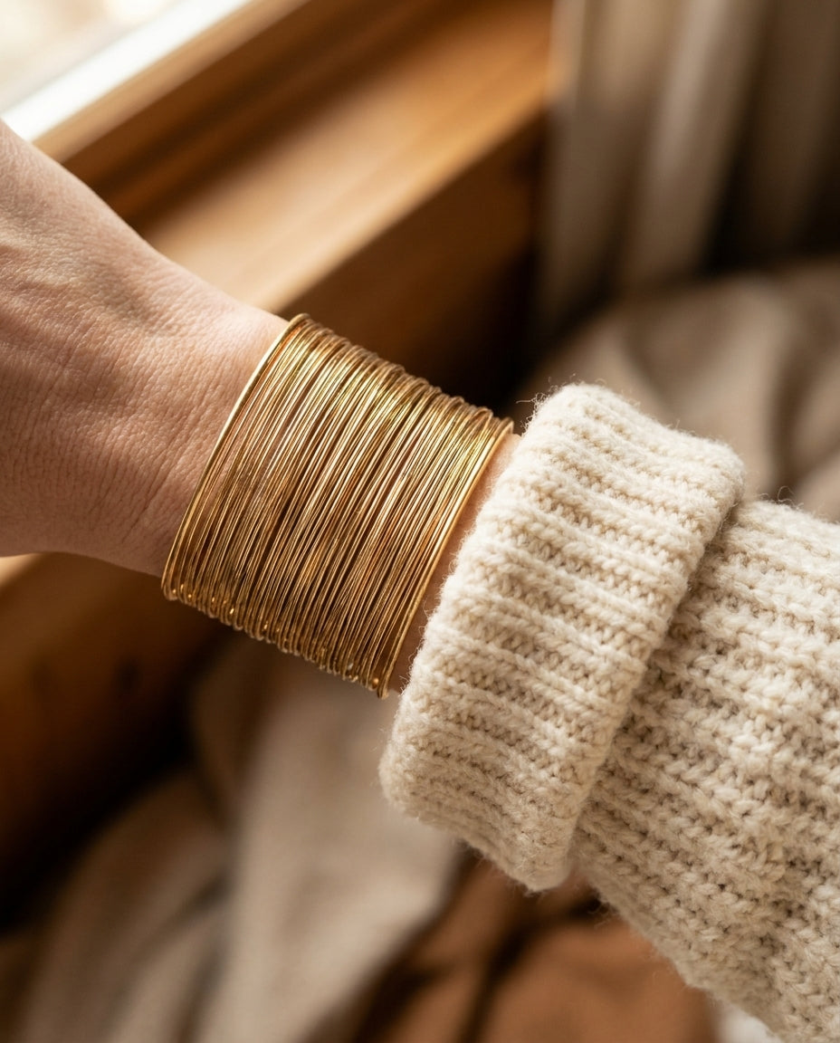 By Sophi Vintage Gold Wire Cuff Bracelet on the wrist over a winter cream knit sleeve