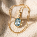 By Sophi Natural Aquamarine Pendant Necklace, catalog flat-lay on warm cream wool