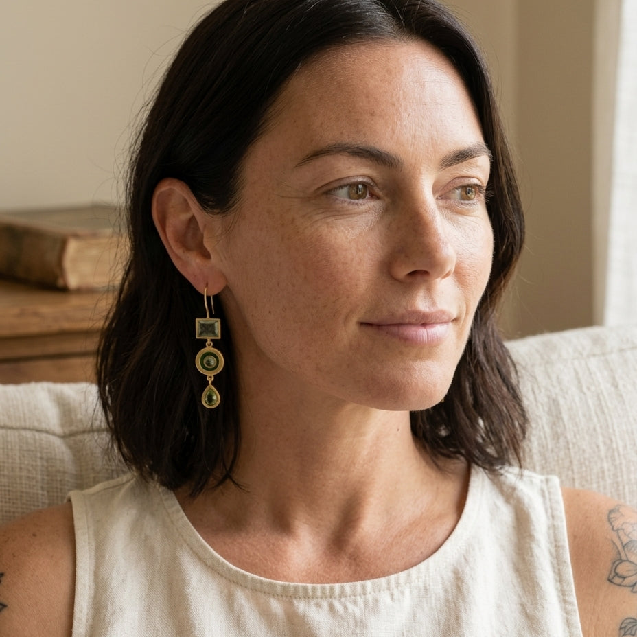 Vintage green dangling earrings on a brunette woman reading in a quiet nook