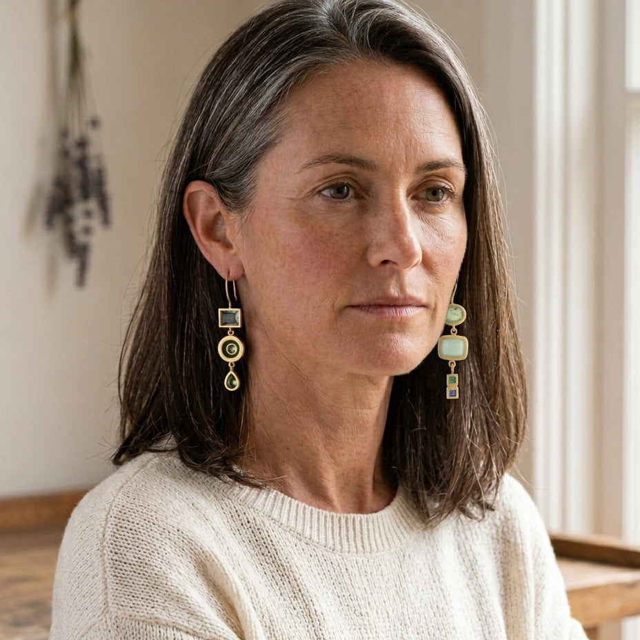 Vintage green dangling earrings on a silver-haired Anglo woman in a workshop