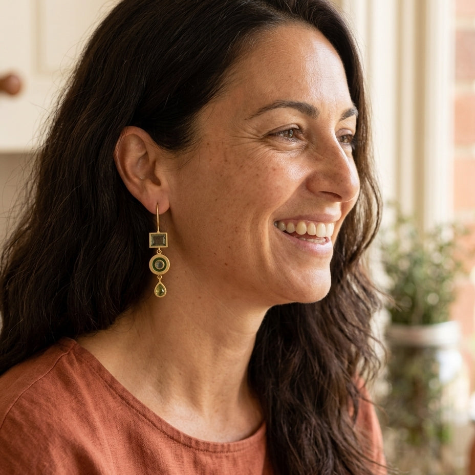 Vintage green dangling earrings on a Mediterranean woman by a sunlit kitchen window