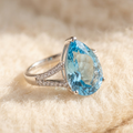 By Sophi Natural Sky Blue Topaz Ring, catalog flat-lay on warm cream wool