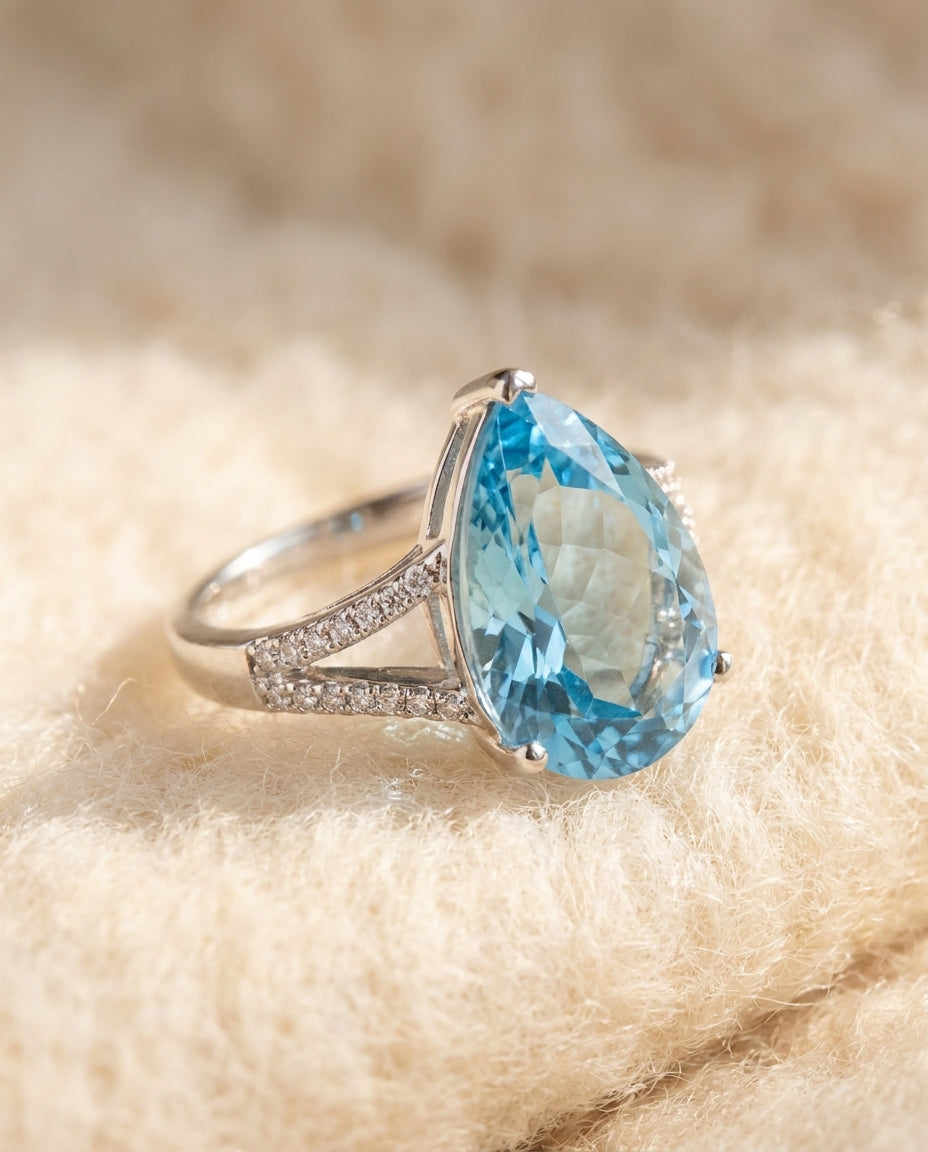By Sophi Natural Sky Blue Topaz Ring, catalog flat-lay on warm cream wool