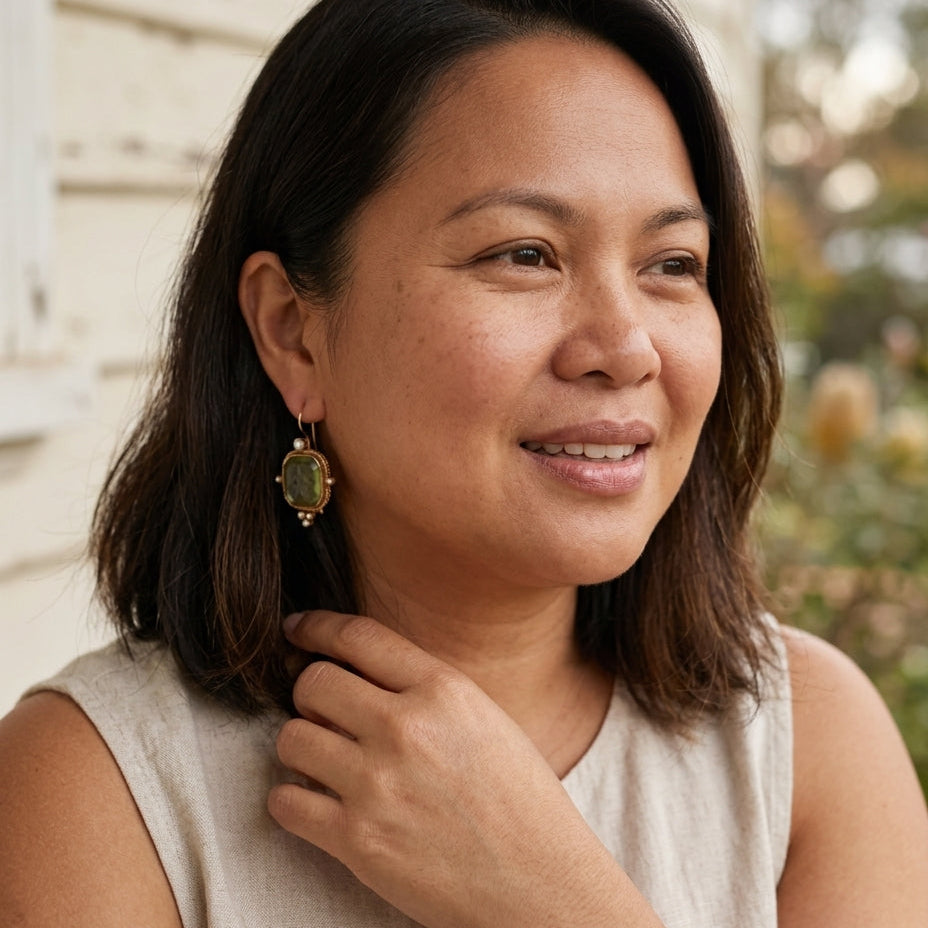 Vintage green and pearl earrings on a Filipino woman seated on a sunlit porch