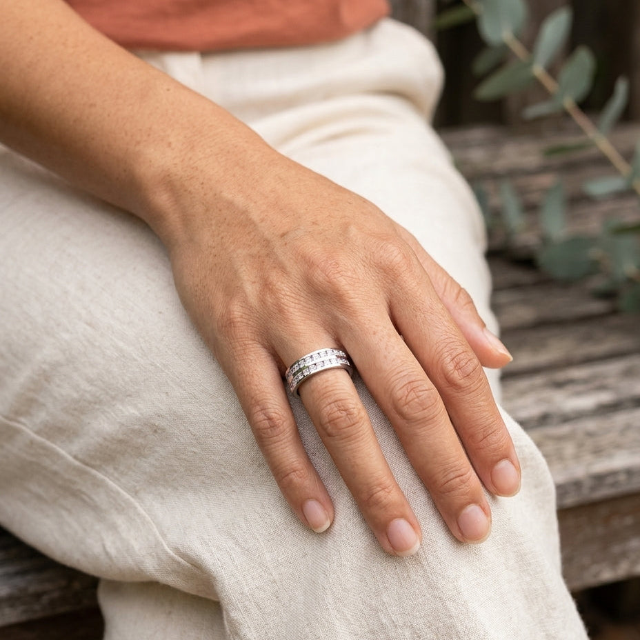 Elegant inlaid zirconia ring on hand resting on knee in a sunlit garden