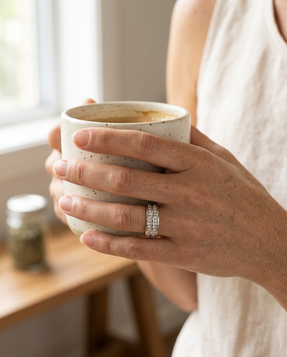 Elegant inlaid zirconia ring on hand wrapped around a kitchen coffee cup