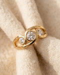 By Sophi Vintage Inlaid Zirconia Spiral Gold Ring flat-lay on warm cream wool