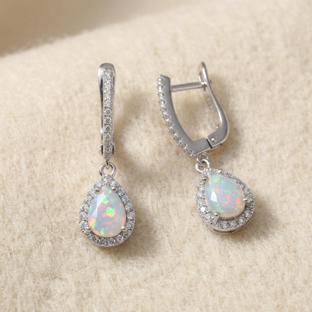 Natural pear-cut opal drop earrings in sterling silver on warm cream wool