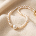 By Sophi Pearl Birthstone Necklace flat-lay on warm cream wool