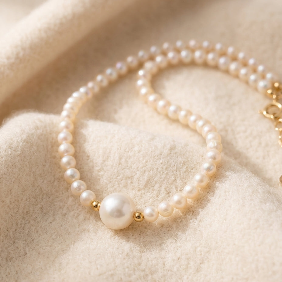 By Sophi Pearl Birthstone Necklace flat-lay on warm cream wool