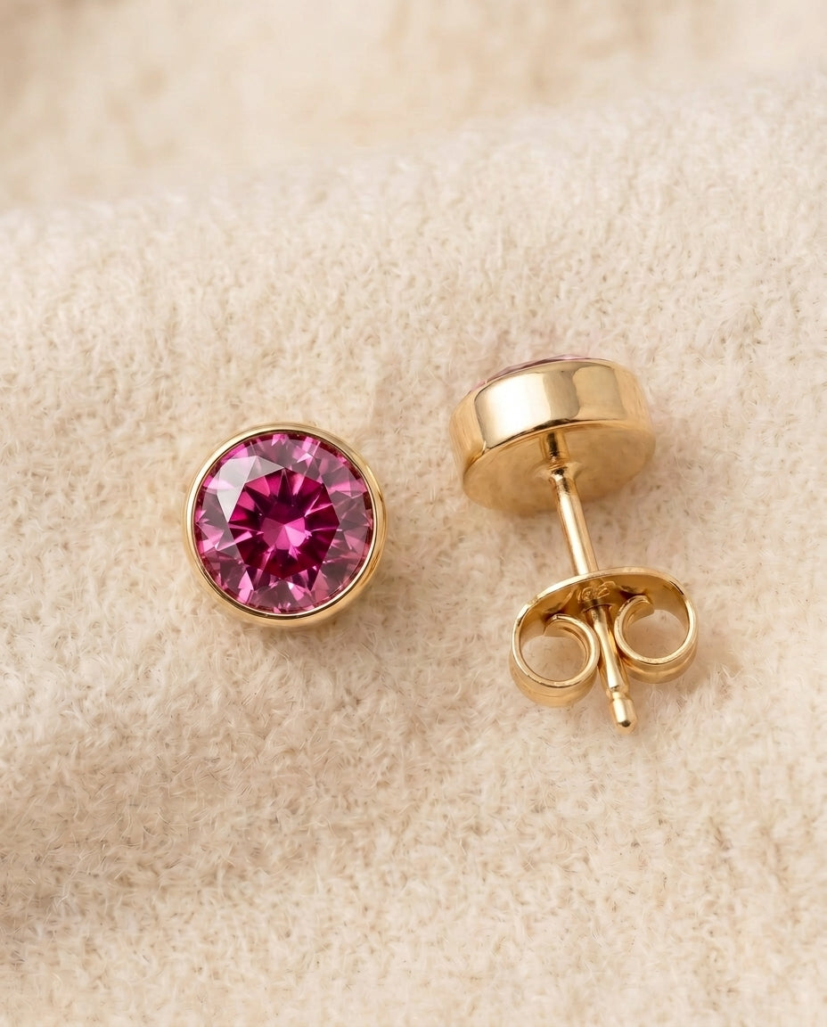 By Sophi Pink Sapphire Birthstone Studs flat-lay on warm cream wool