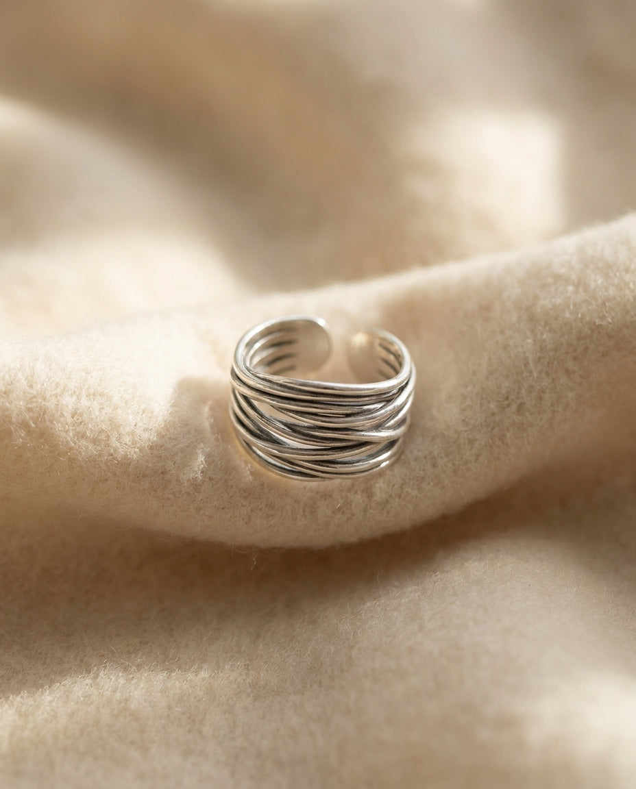 By Sophi Silver Adjustable Layered Ring flat-lay on warm cream wool