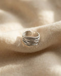 By Sophi Silver Adjustable Layered Ring flat-lay on warm cream wool