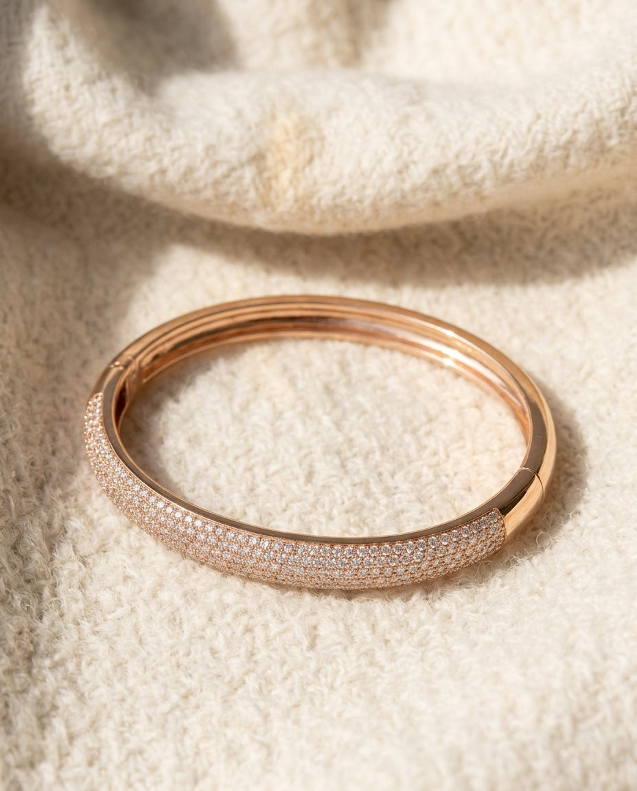 By Sophi Rose Gold Zirconia Bangle flat-lay on warm cream wool