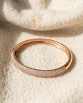 By Sophi Rose Gold Zirconia Bangle flat-lay on warm cream wool