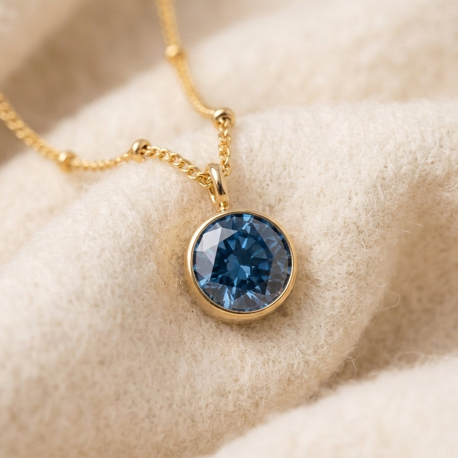 By Sophi Sapphire Birthstone Pendant Necklace flat-lay on warm cream wool