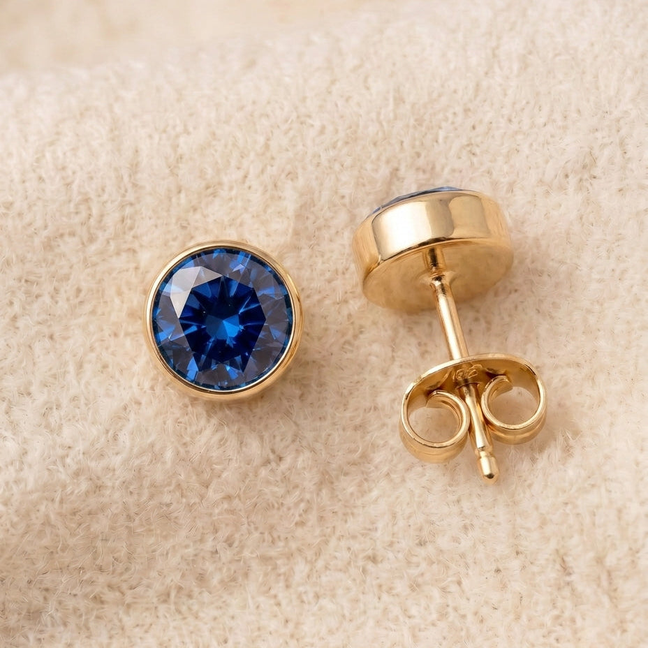 By Sophi Sapphire Birthstone Studs flat-lay on warm cream wool