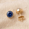 By Sophi Sapphire Birthstone Studs flat-lay on warm cream wool