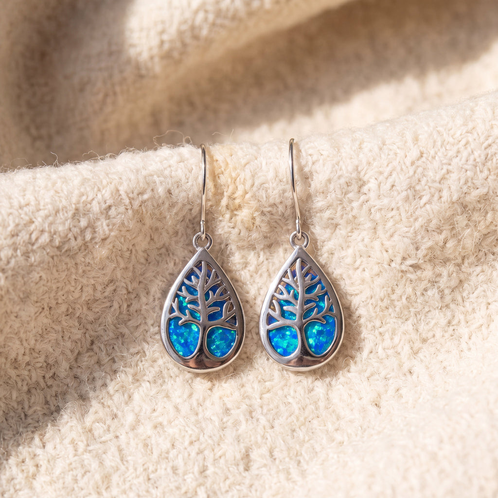 By Sophi Tree of Life Opal Sterling Silver Earrings flat-lay on warm cream wool