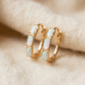 Vintage opal gold huggie hoop earrings on cream textile, three white opal bar inlays per hoop with gold prong settings