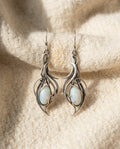 By Sophi Vintage White Opal Silver Scroll Earrings flat-lay on warm cream wool