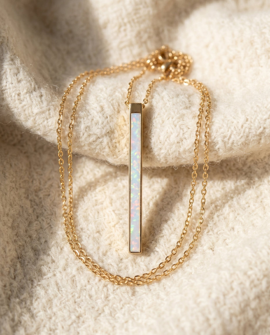 By Sophi White Opal Pendant in Gold bar flat-lay on warm cream