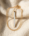 By Sophi White Opal Pendant in Gold bar flat-lay on warm cream